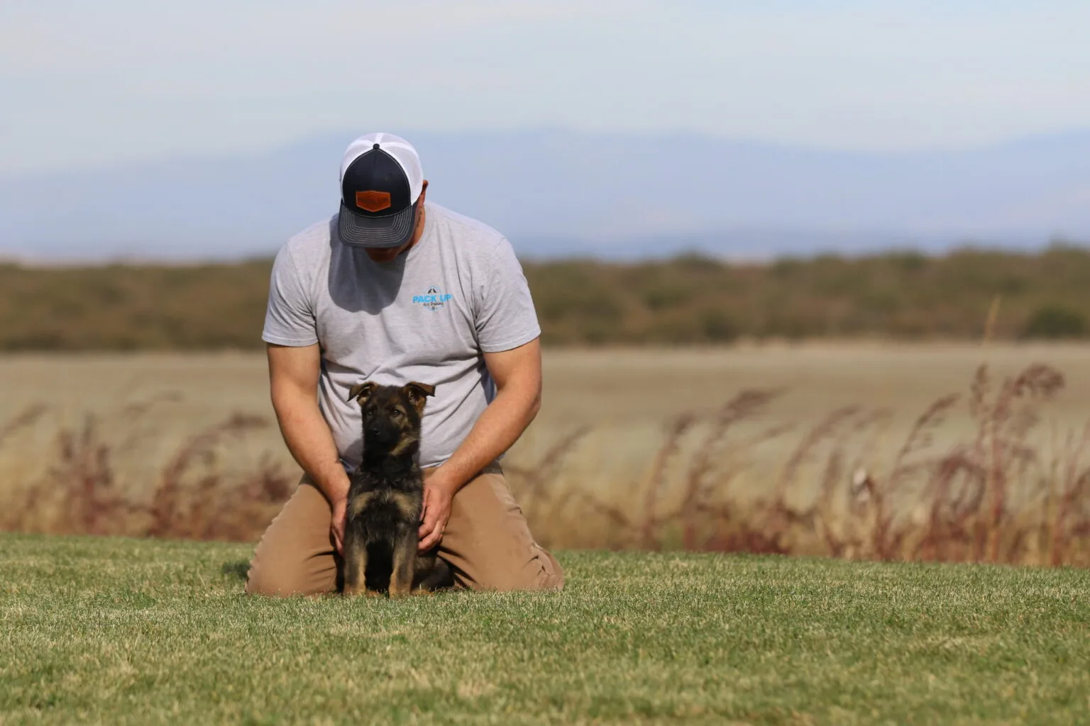 A man kneeling down with his dog in the grass.