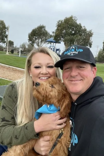 A man and woman holding a dog in their arms.