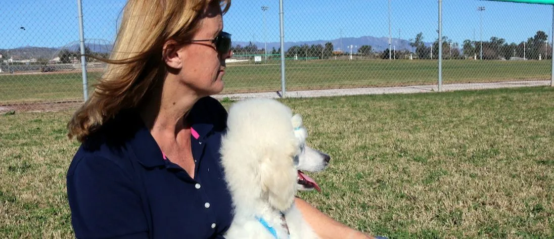 woman in blue shirt holding poodle dog