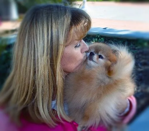 woman wearing pink with blonde hair holding dog